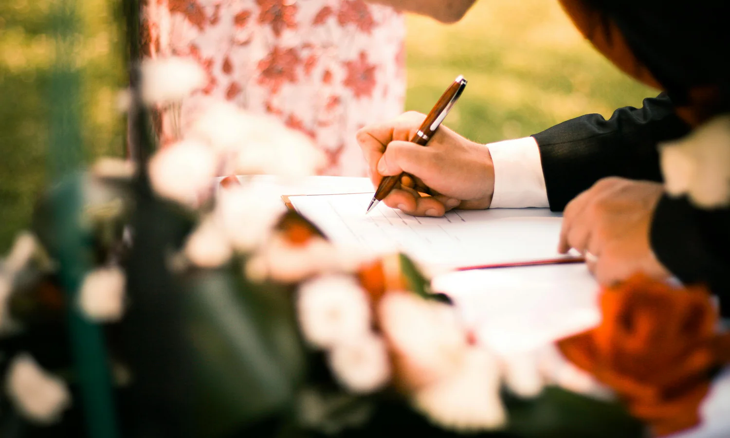 Signature d’un contrat d’assurance vie sur une table, un bouquet de fleurs en arrière-plan